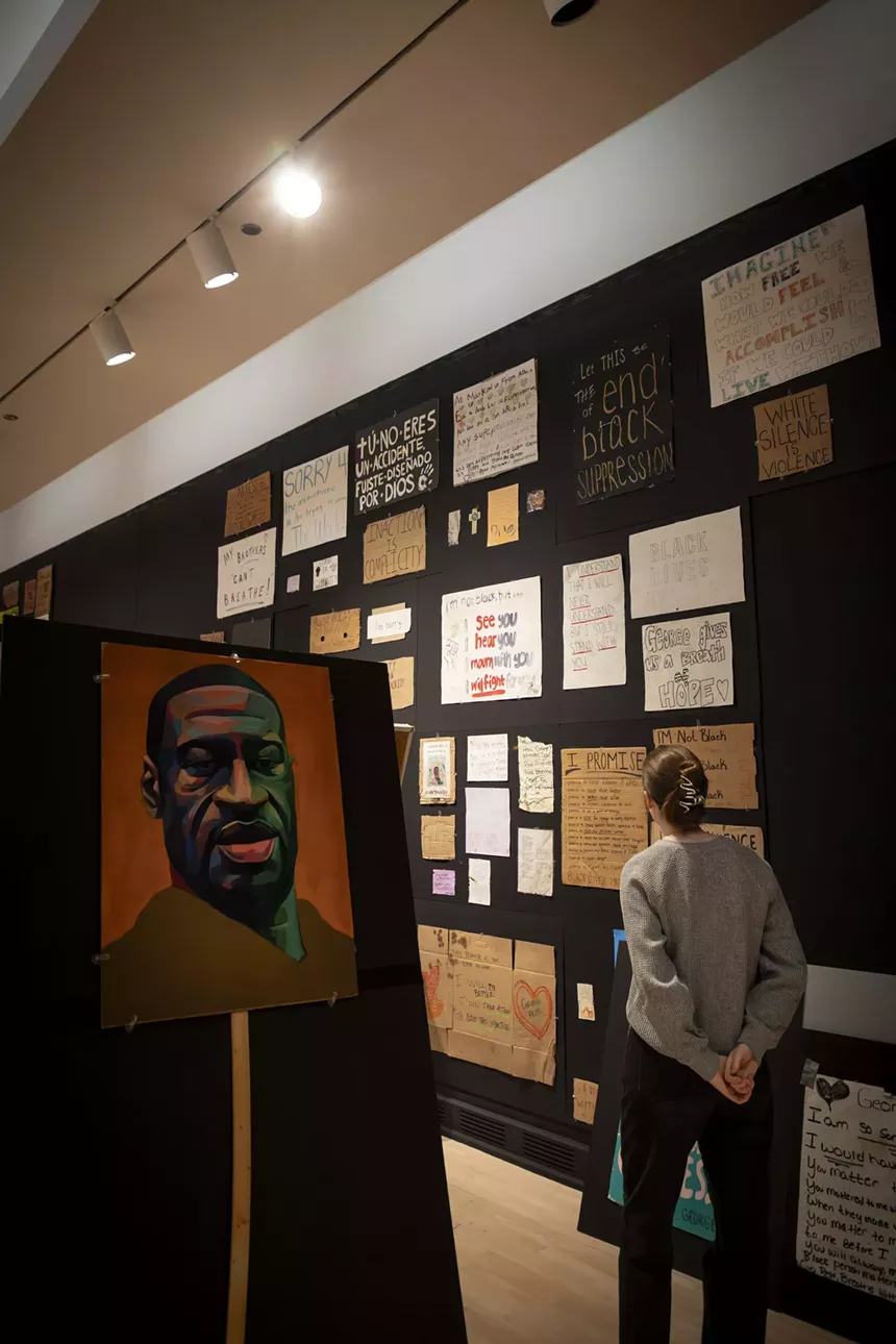 A woman looks at items in an art museum exhibition.