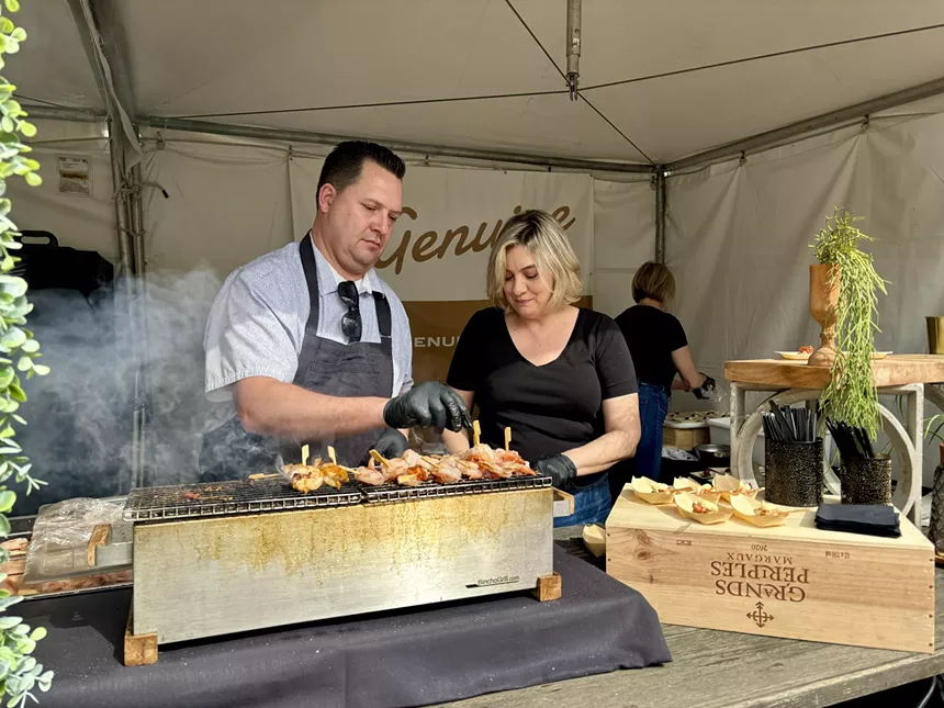 Man grills shrimp at a table.