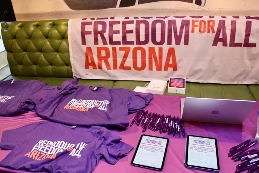T-shirts, pens and an iPad placed on a table.