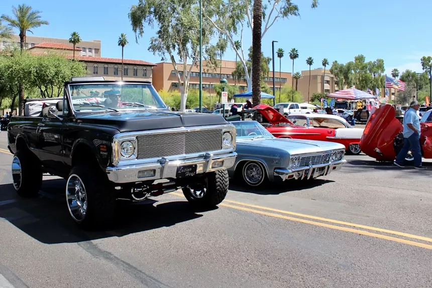 Cars lined up in front of clear skies and trees.