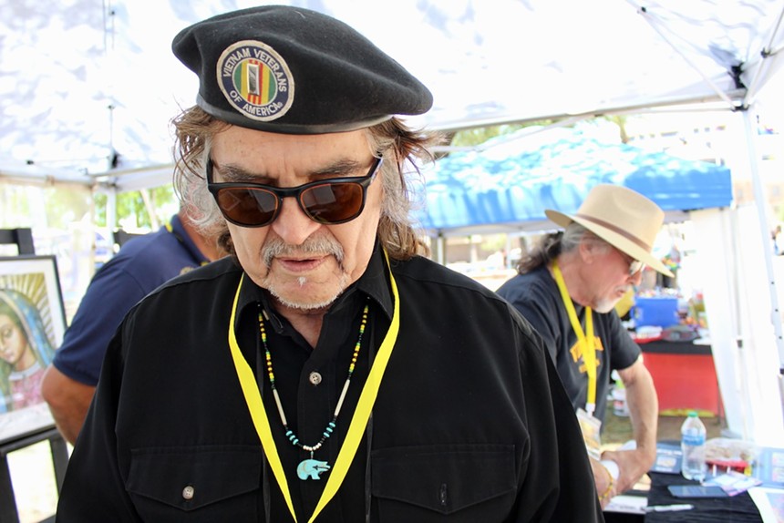 A man looking down wears a beret and sunglasses.