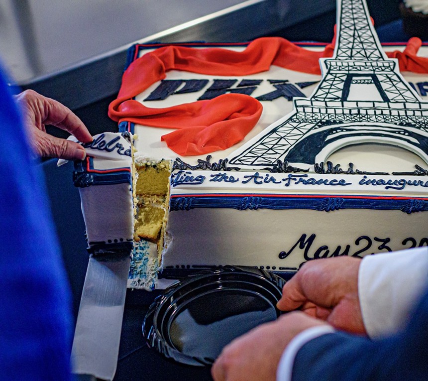 Someone cuts a cake with the Eiffel Tower on it.