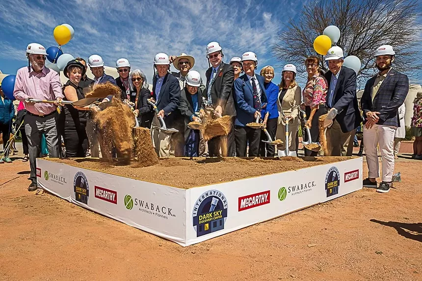 People in construction hats at a groundbreaking.