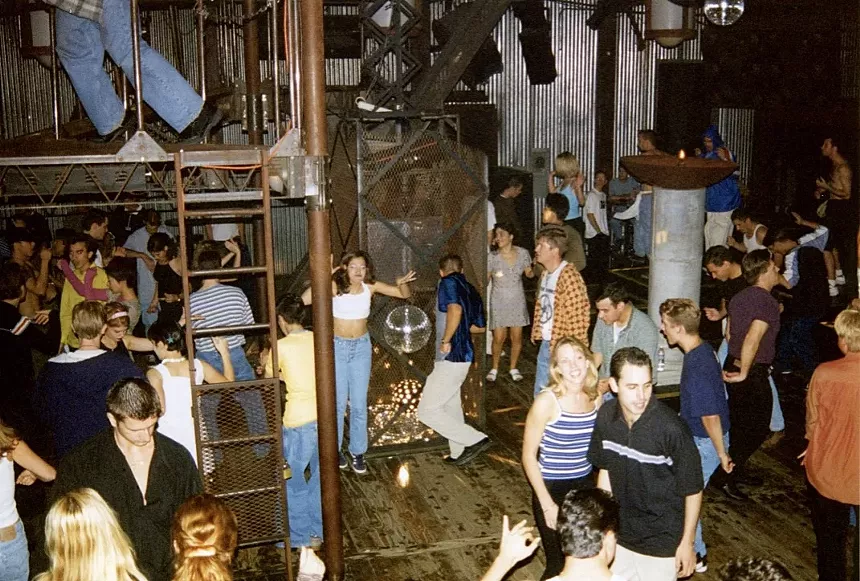 A crowd of dancers inside a '90s nightclub.