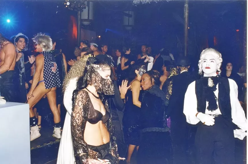 A crowd of costumed people crowd the dance floor at a nightclub.
