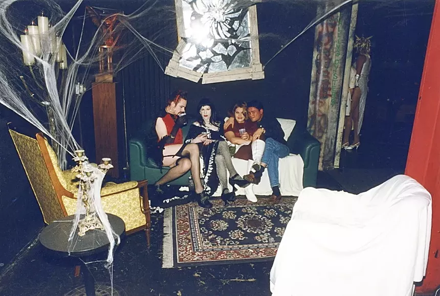A group of people sitting on a couch inside a nightclub.