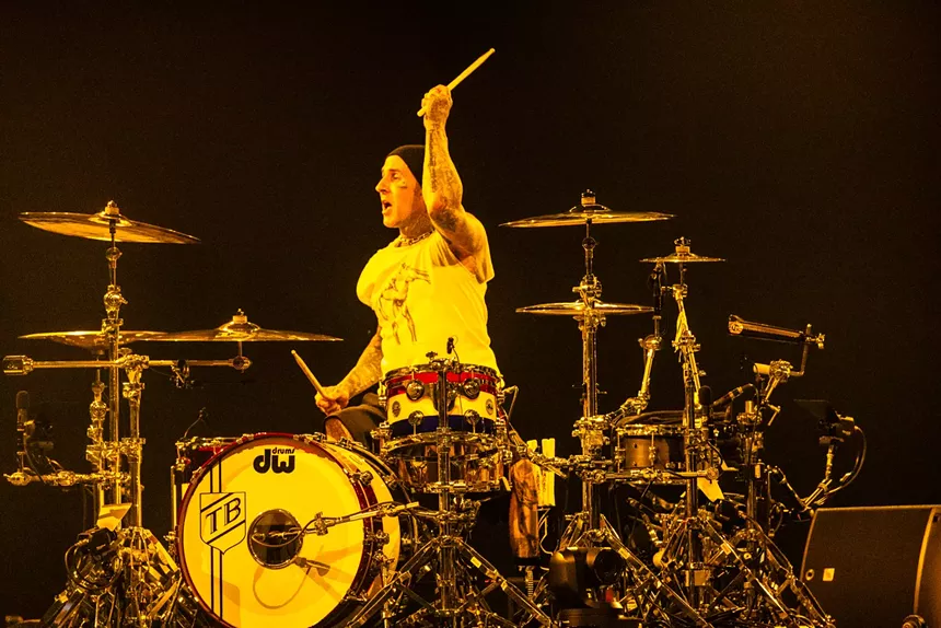 A man playing the drums under yellow lights.