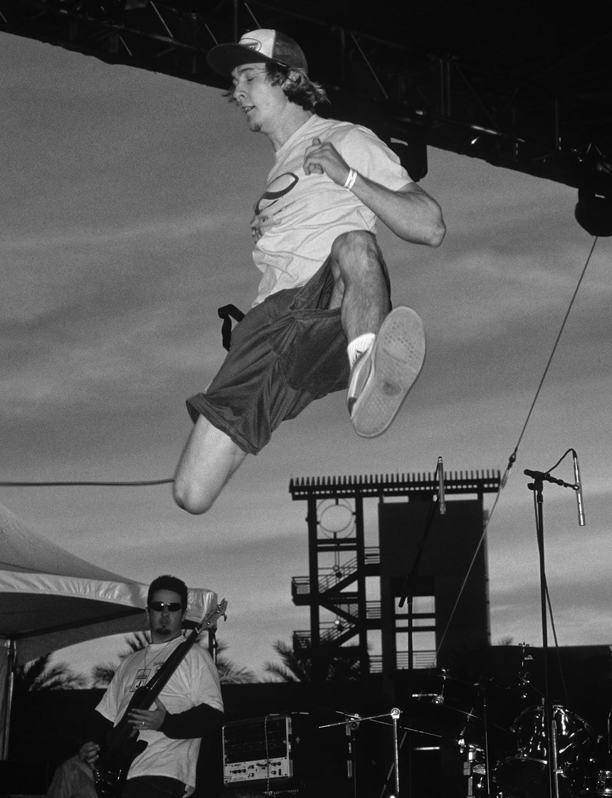 A singer jumping in the air at a music festival.