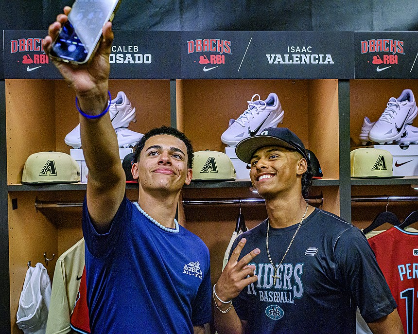 Two high school baseball players take a selfie in front of a locker