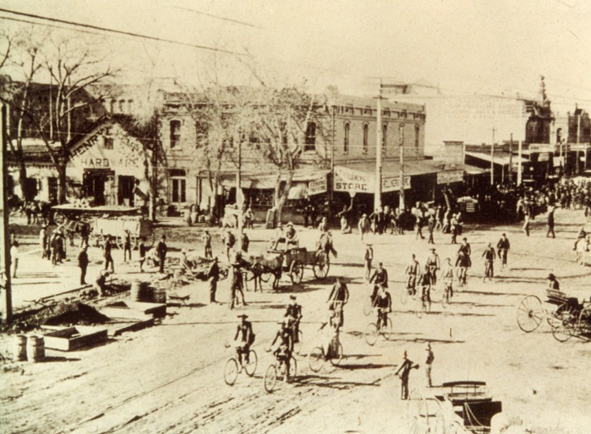 a 1900s photo of a phoenix street with people on bicycles and one horse-drawn carriage