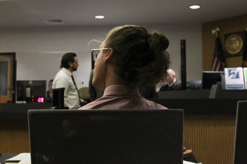 A man, seen from behind, sits in a courtroom.
