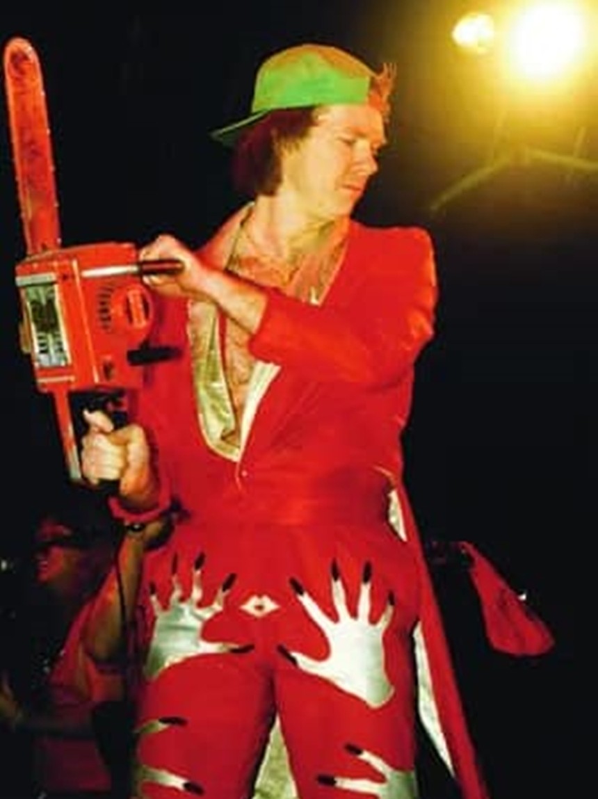 A man dressed in red holding a chainsaw.