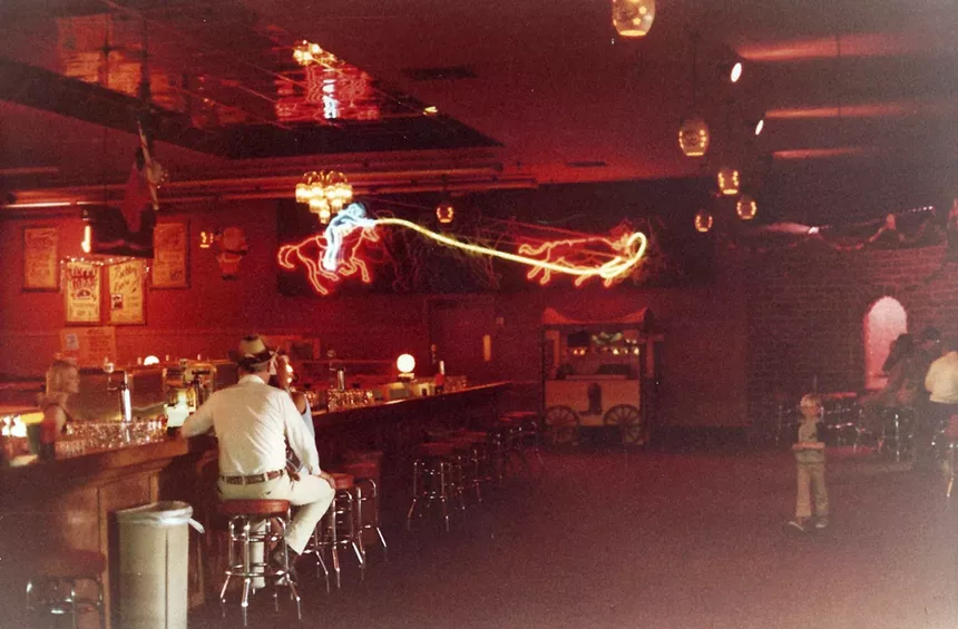 A bar and seating area in a large room inside a nightclub.