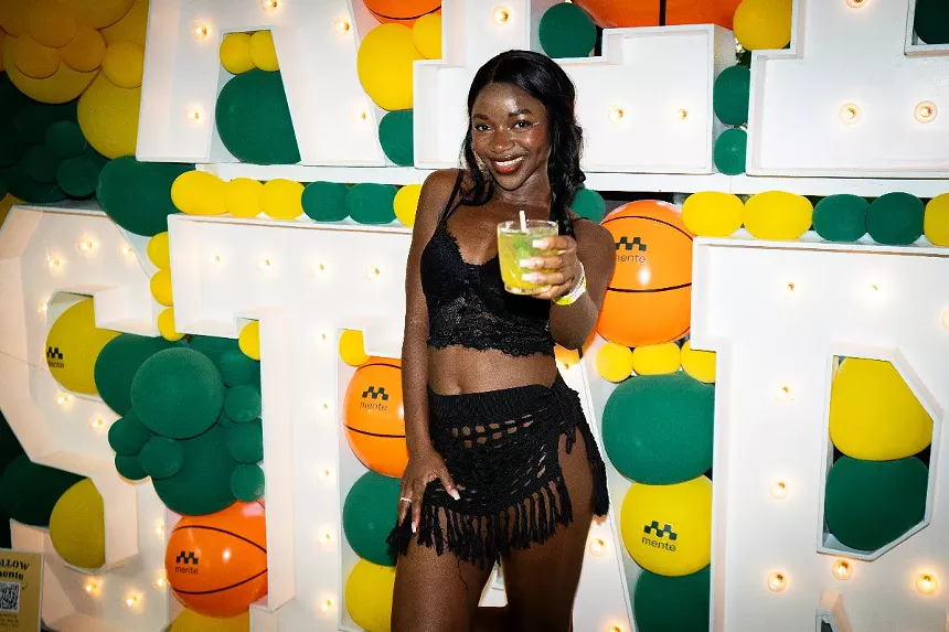 A woman poses with a drink in hand