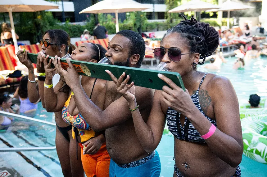Four people take shots of alcohol lined up on a board