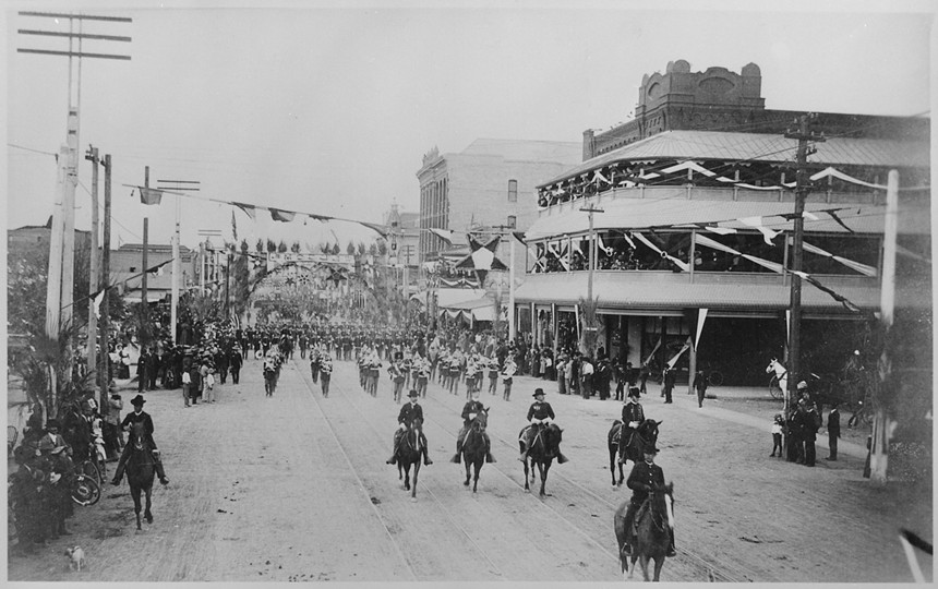 A military parade down a street in 1888 in an old photograph