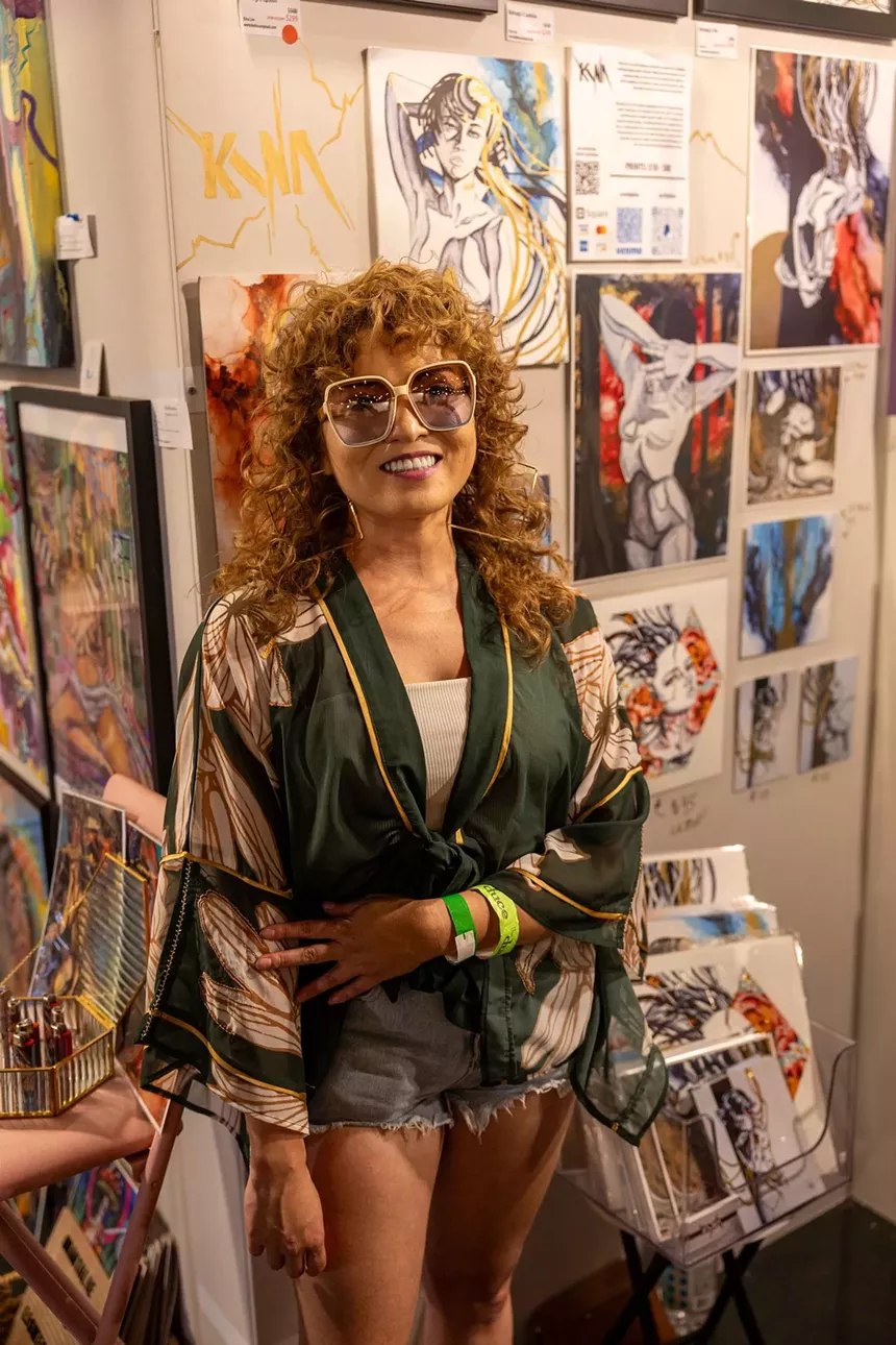 A woman standing in front of a wall of art.