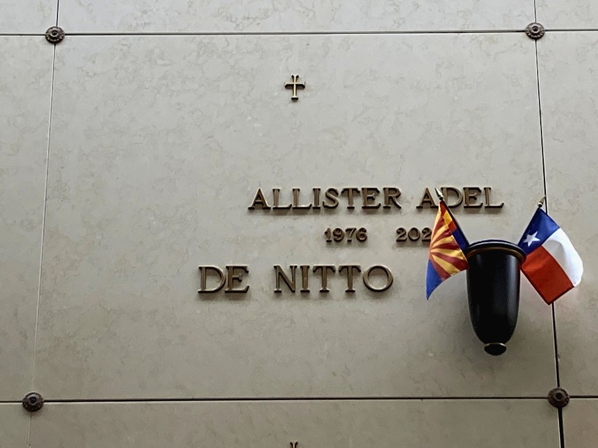 A grave marker for Allister Adel DeNitti, with Arizona and Texas flags on it