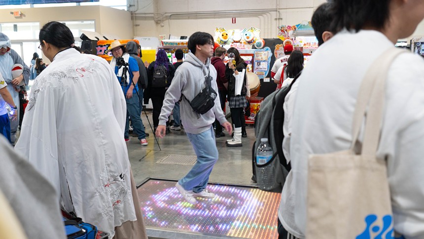A person playing a video game in a crowded vendor hall.