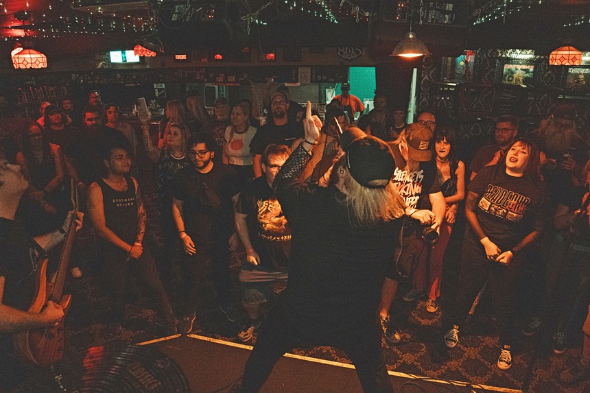 A rock vocalist sings onstage in front of a crowd.