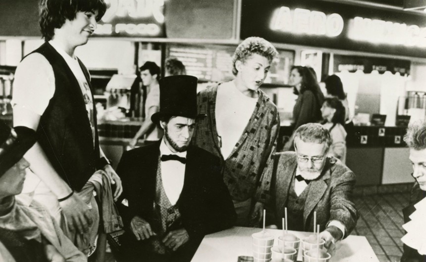 Two stoners and several historical figures around a mall food court table.