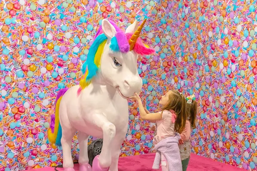 Two little girls with a unicorn statue.