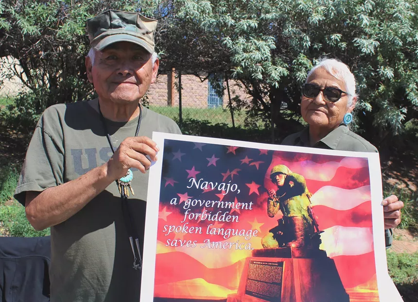 A man holds a poster with a woman standing nearby.
