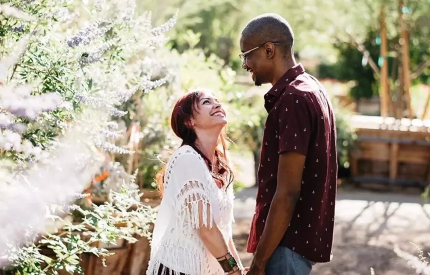 a woman and man hold hands and look into each other's eyes smiling