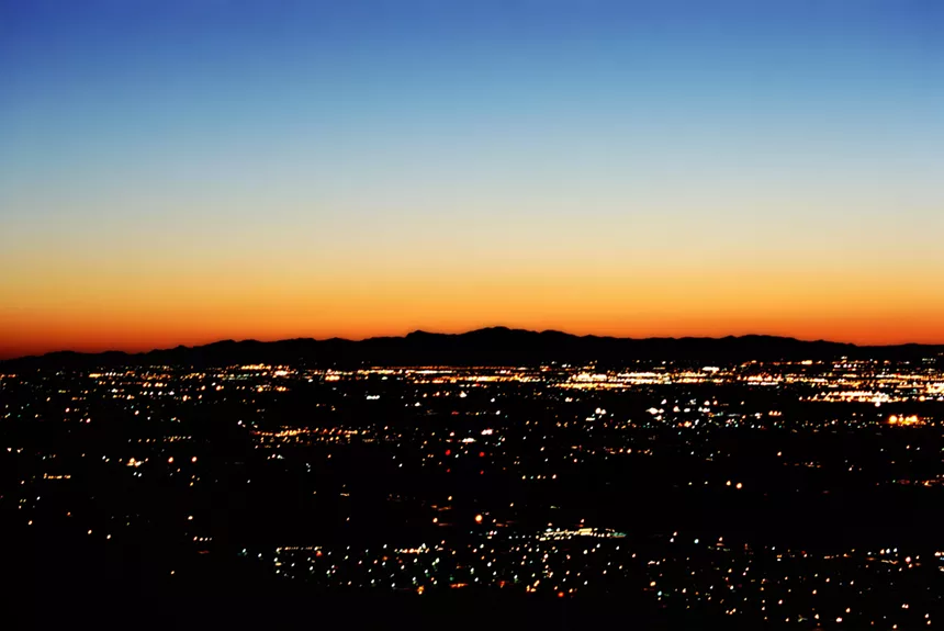 A city at sunset as seen from a mountain.