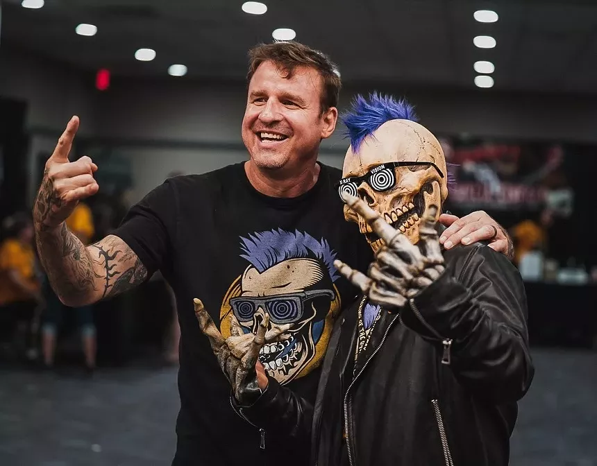 A man standing next to a person in a skeleton costume.
