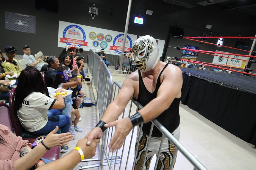 A masked wrestler shakes a fan's hand.