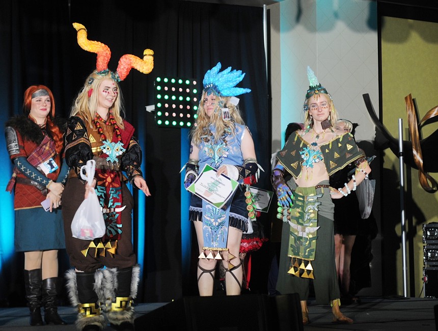 Three cosplayers standing on a stage.