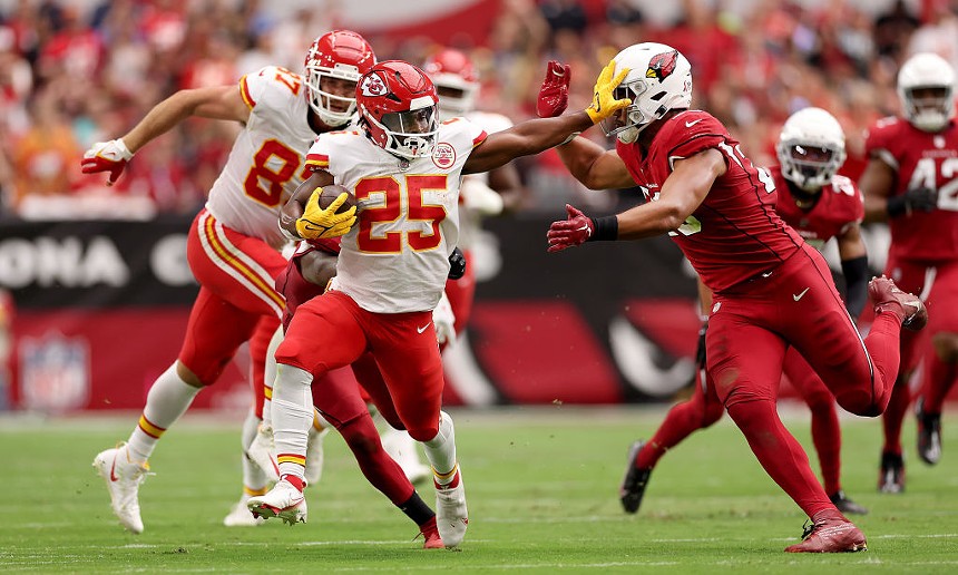 a chiefs running back stiff-arms a cardinals defender