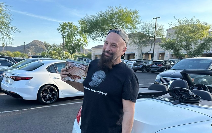 a man in a larry david shirt, with a backward hat on and a long beard