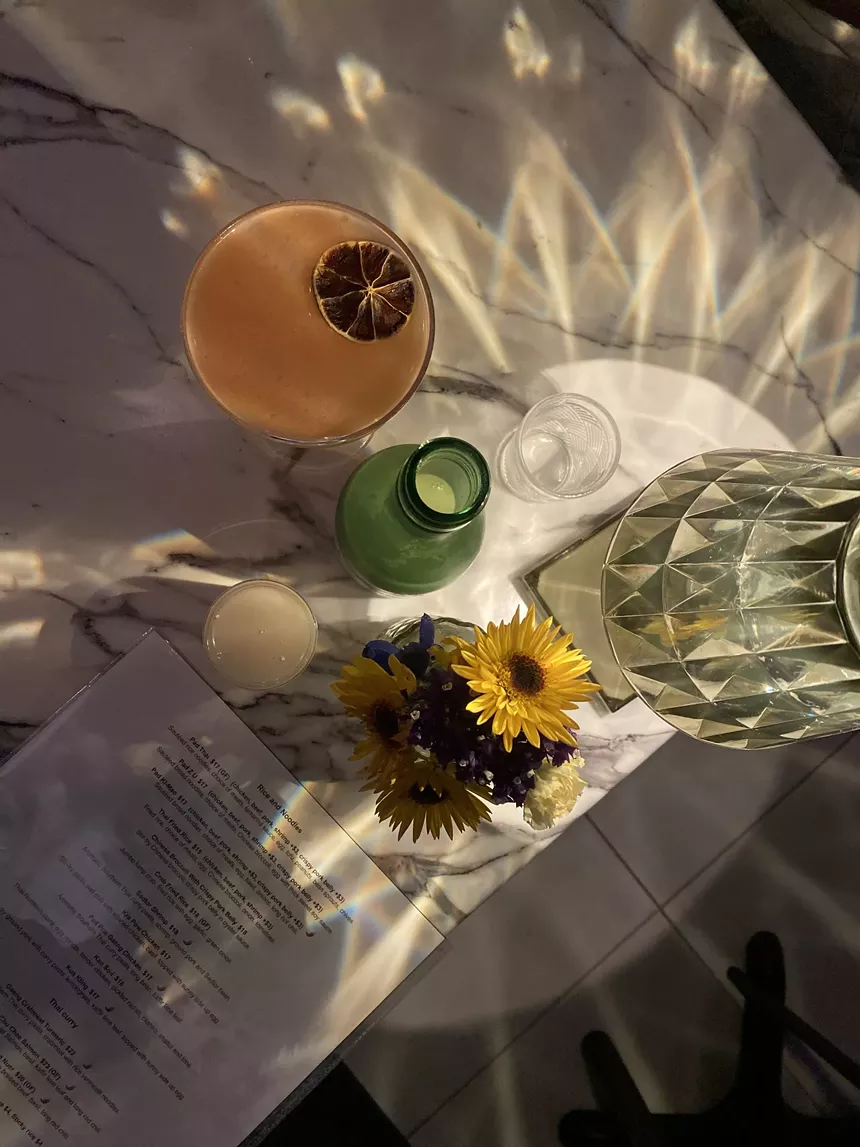 a cocktail and an open glass bottle on a table