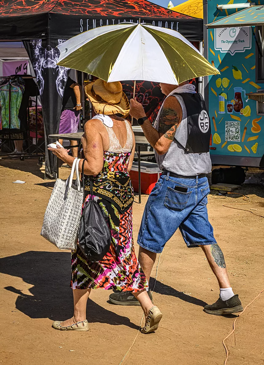two people walk under an umbrella on a sunny day