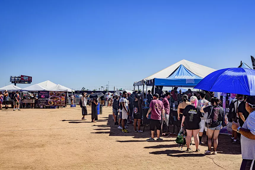 people wait outside booths on a cloudless day