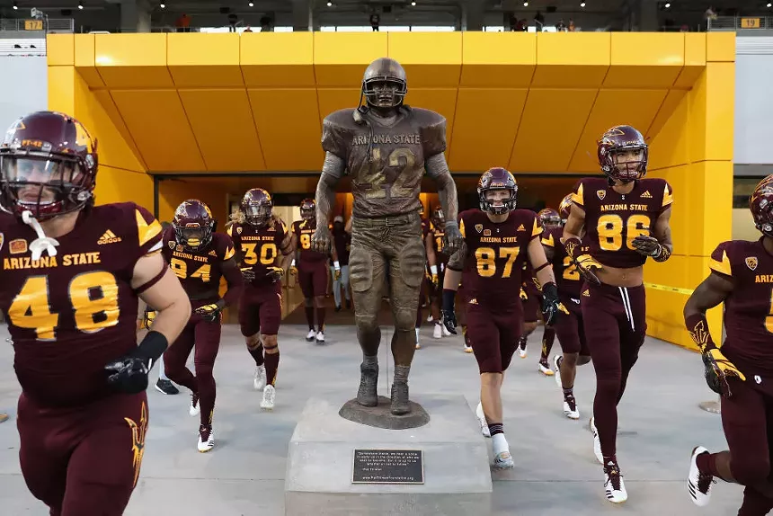 Arizona State players run past the Pat Tillman statue before a 2017 game.