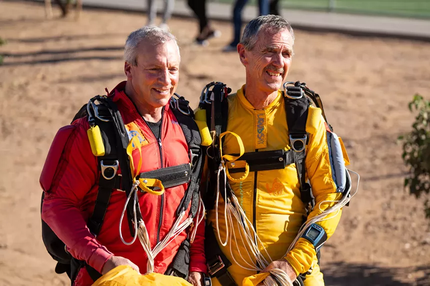 two senior citizen skydivers, one in red and the other in yellow