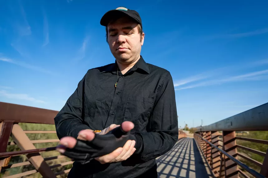 a man in a black shirt holds out his left hand, which is in a protective sleeve