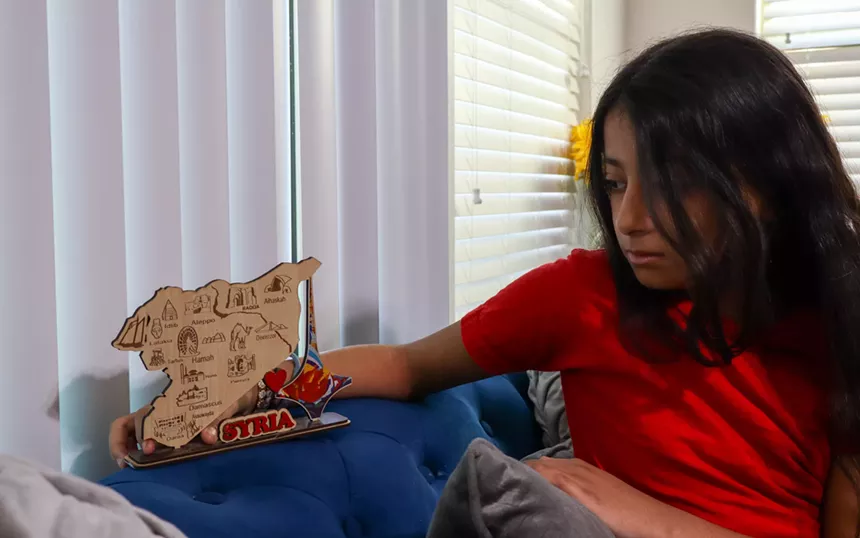 a young syrian girl looks at a map of syria