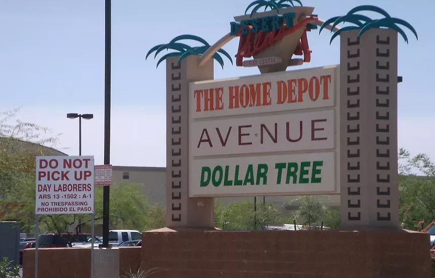 a sign posted near a shopping center that says "do not pick up day laborers"