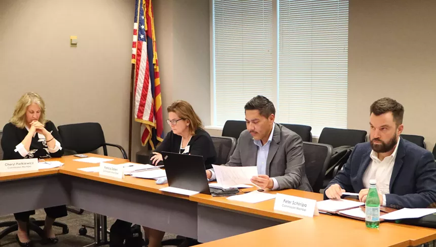 people sit around a table at a government meeting