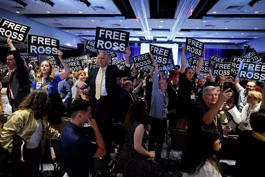 people stand on chairs while holding "free ross" signs