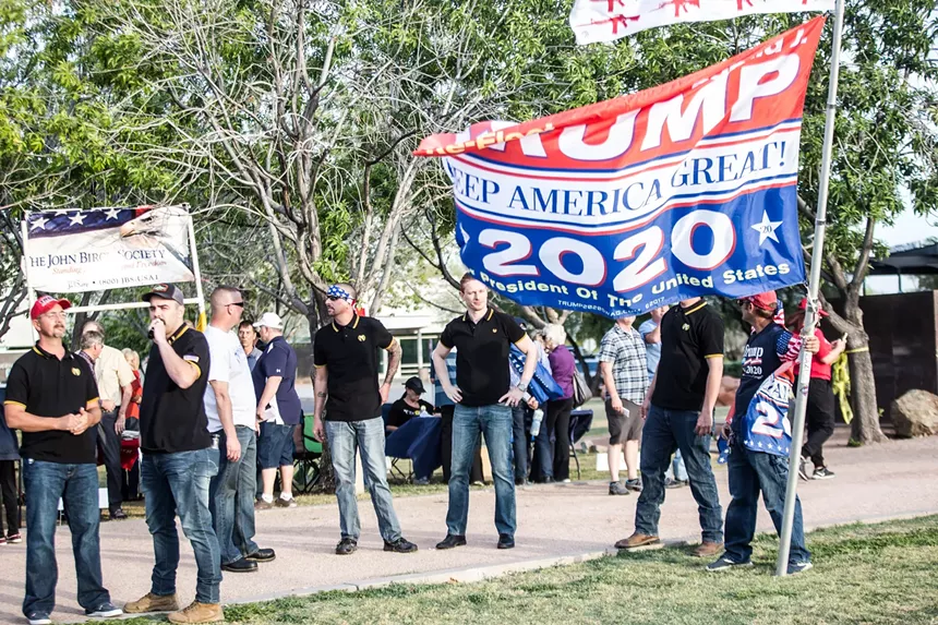 people in black shirts on a sidewalk