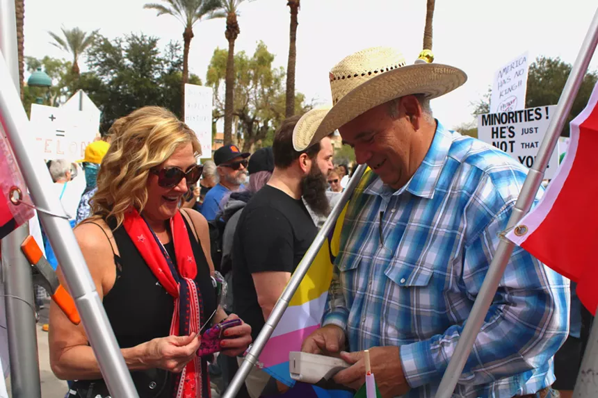 a man in a cowboy hat sells something to a woman at a protest
