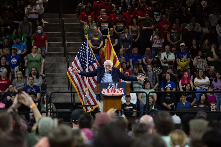 bernie sanders with arms outstretched at a rally