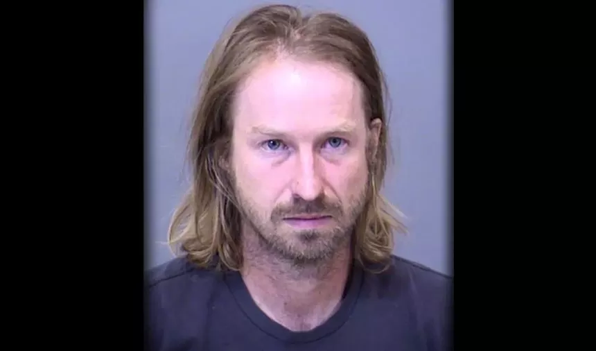 a mugshot of a man with long blond hair