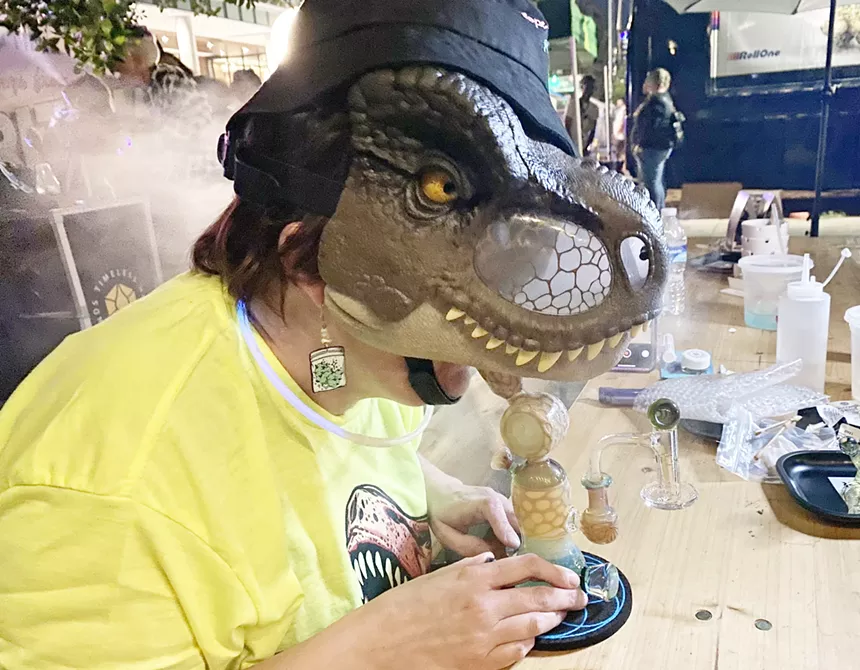 a person in a dinosaur mask hits a dab rig