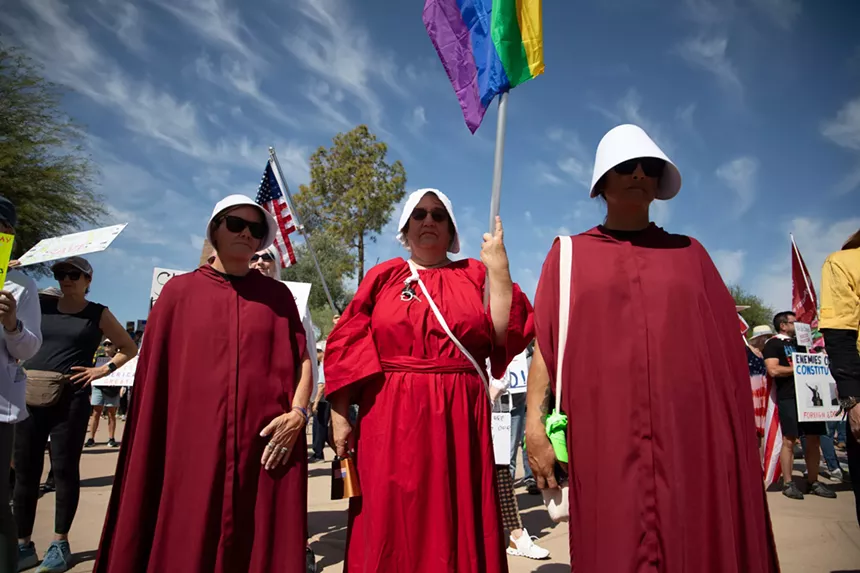 three women dress as characters from a handmaid's tale